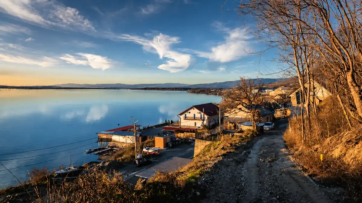 Coronini village along the calm Danube shoreline in golden afternoon light